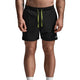 A man wearing black athletic shorts with a bright lime green drawstring, paired with white socks and white sneakers, shown from the waist down against a gray studio background.