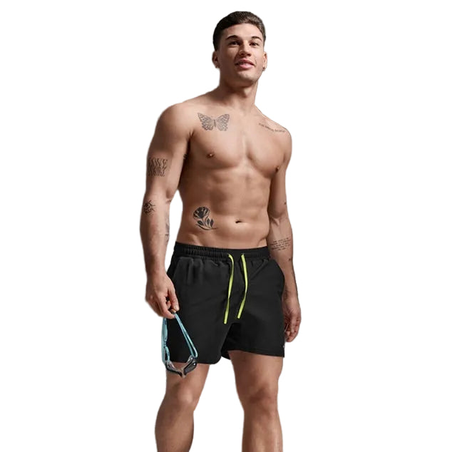 Man wearing black swim shorts with a yellow drawstring against a gray background