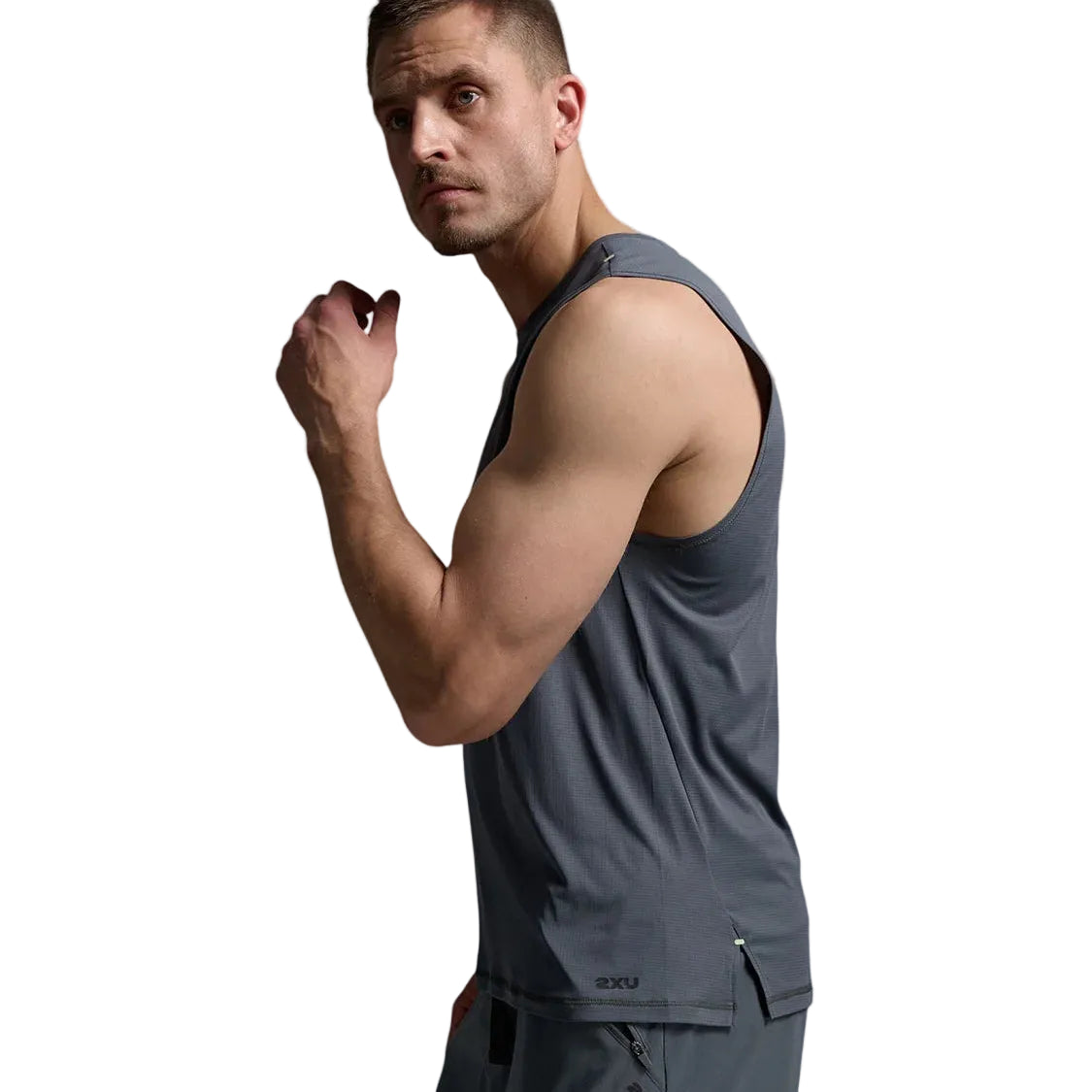 A man wearing a dark gray sleeveless athletic tank top and matching gray shorts, posed against a light gray studio background.