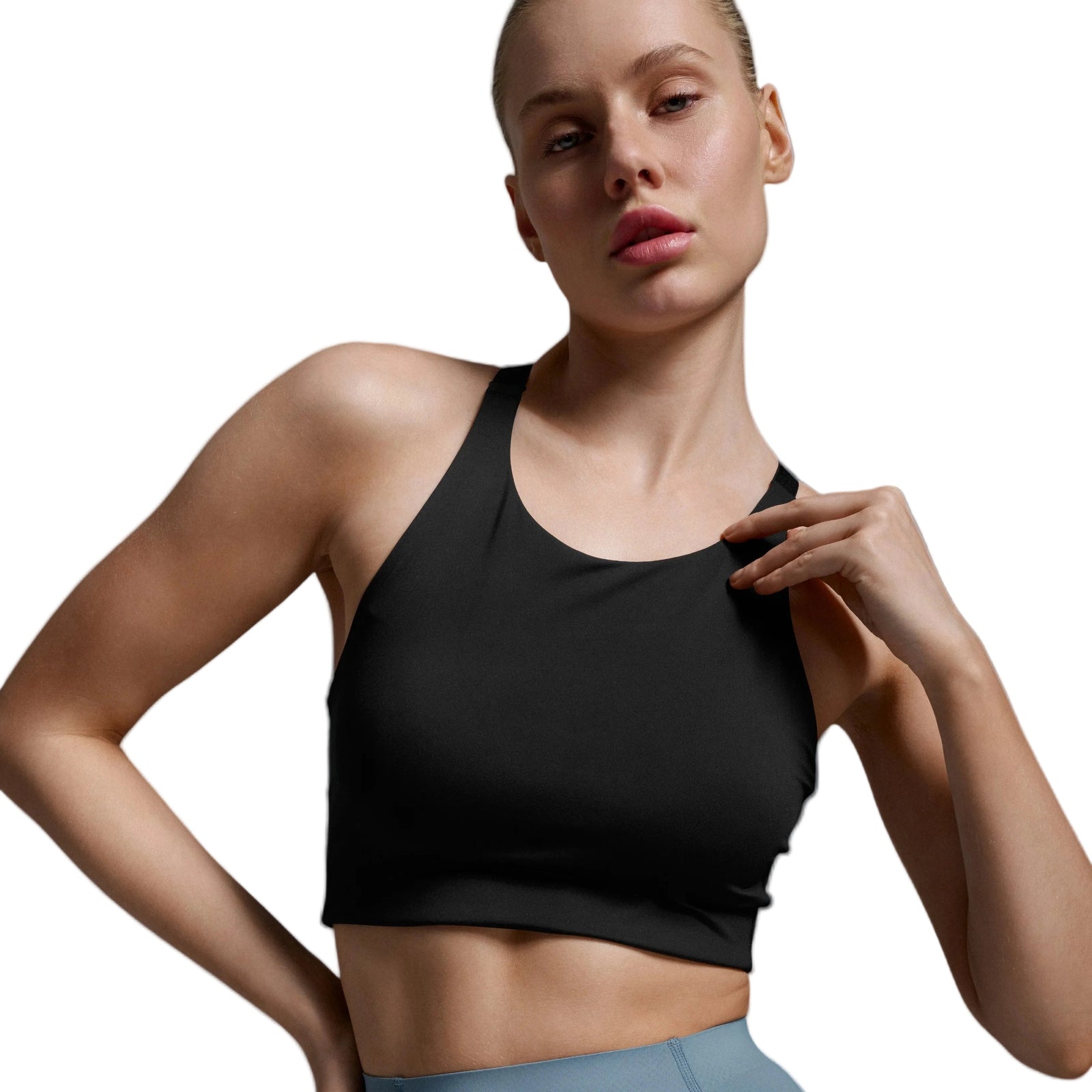 A woman modeling a black athletic crop top and dusty blue high-waisted leggings against a light gray studio background.