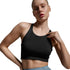 A woman modeling a black athletic crop top and dusty blue high-waisted leggings against a light gray studio background.