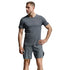 A man modeling a dark gray athletic t-shirt and matching shorts against a light gray studio background.