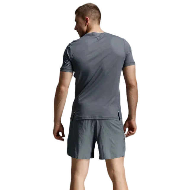 A man shown from behind wearing a dark gray athletic t-shirt and matching shorts, paired with white socks and running shoes, against a light gray studio background.