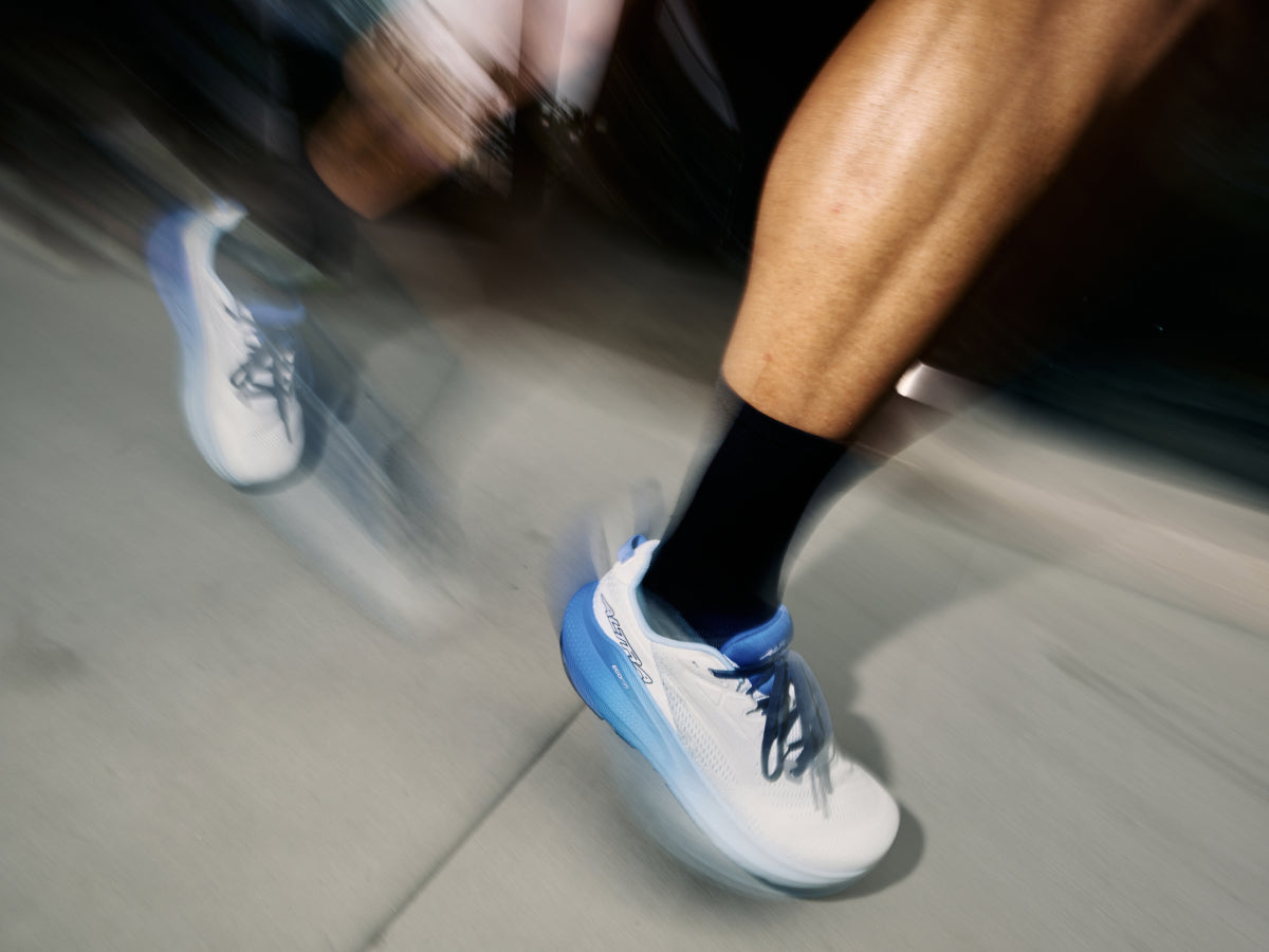 man running in white and blue shoes in an urban setting