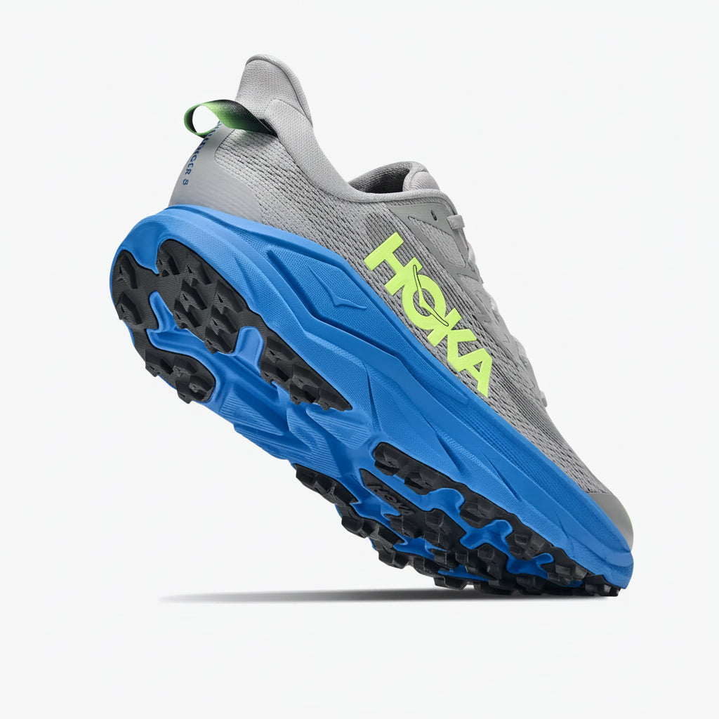 A Hoka trail running shoe in gray and blue with a bright neon green HOKA logo on the side, shown from a three-quarters angle against a light gray background.