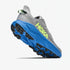 A Hoka trail running shoe in gray and blue with a bright neon green HOKA logo on the side, shown from a three-quarters angle against a light gray background.