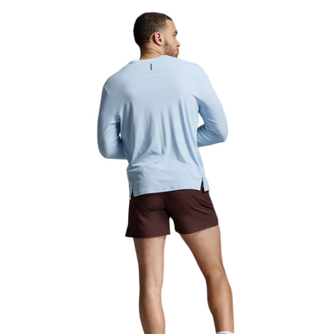 A man shown from the back wearing a light blue long-sleeve athletic shirt against a light gray studio background.