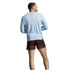 A man shown from the back wearing a light blue long-sleeve athletic shirt against a light gray studio background.