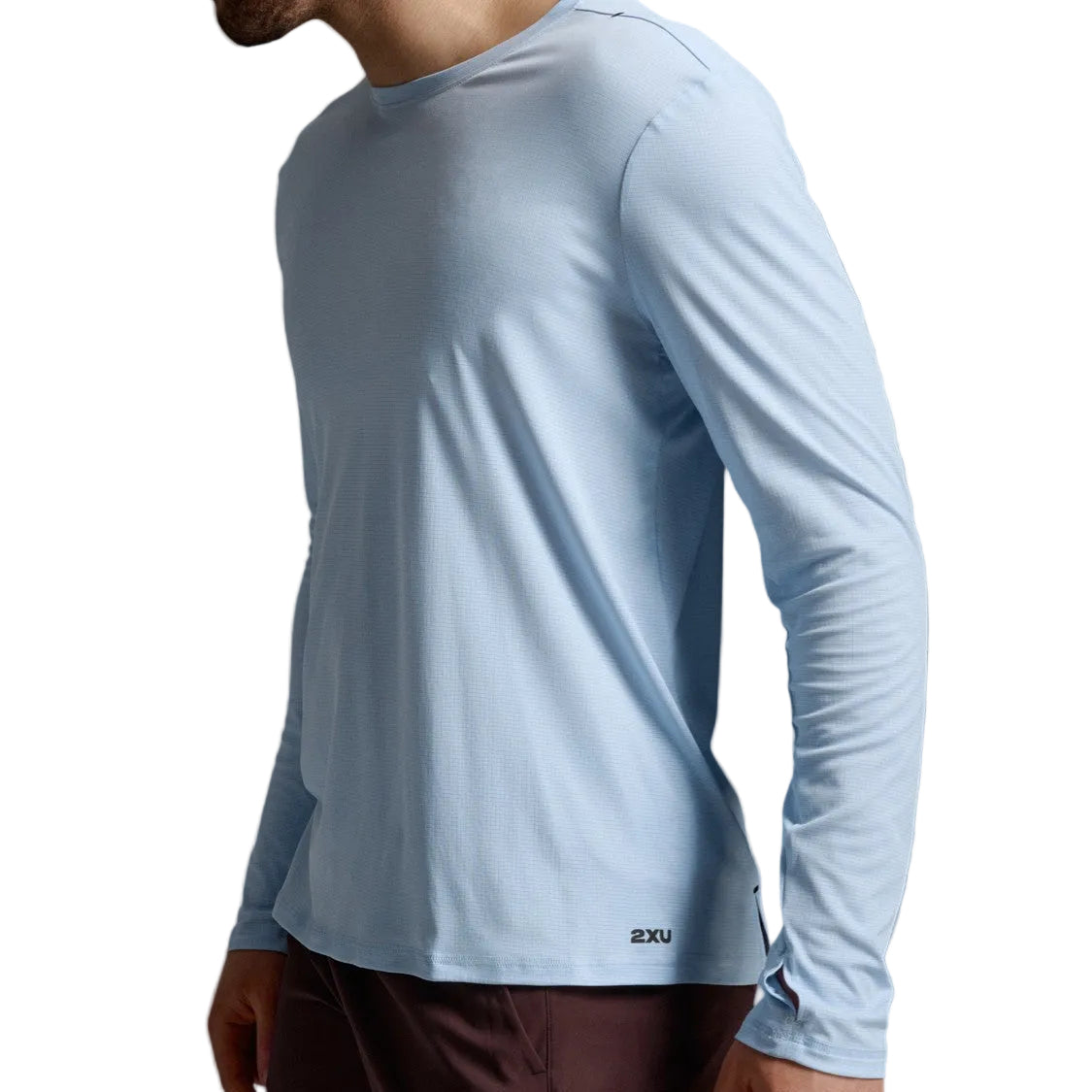 A man wearing a light blue long-sleeve athletic shirt and dark brown shorts, shown from a side profile against a neutral gray studio background.