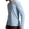 A man wearing a light blue long-sleeve athletic shirt and dark brown shorts, shown from a side profile against a neutral gray studio background.