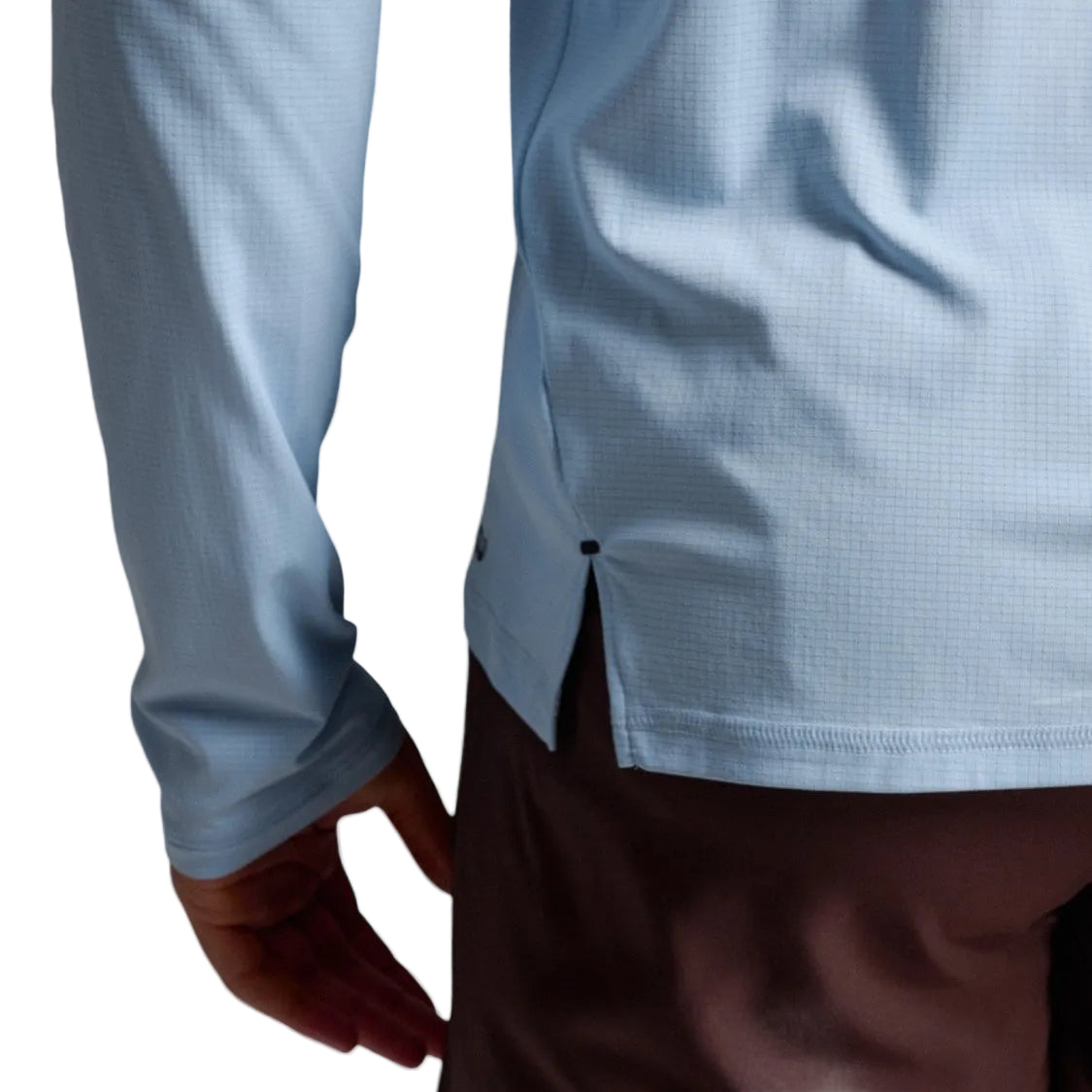 Close-up of a person wearing a light blue long-sleeve textured shirt.