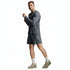 A man modeling a dark gray long-sleeve athletic shirt and matching shorts, paired with off-white socks and beige sneakers, against a light gray studio background.