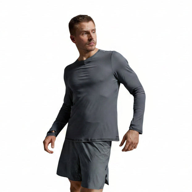 A man wearing a dark gray long-sleeve athletic shirt and matching gray shorts, photographed against a light gray studio background.