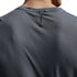 Close-up back view of a person wearing a dark gray textured athletic t-shirt, showing the neck collar and a small vertical black brand tag.