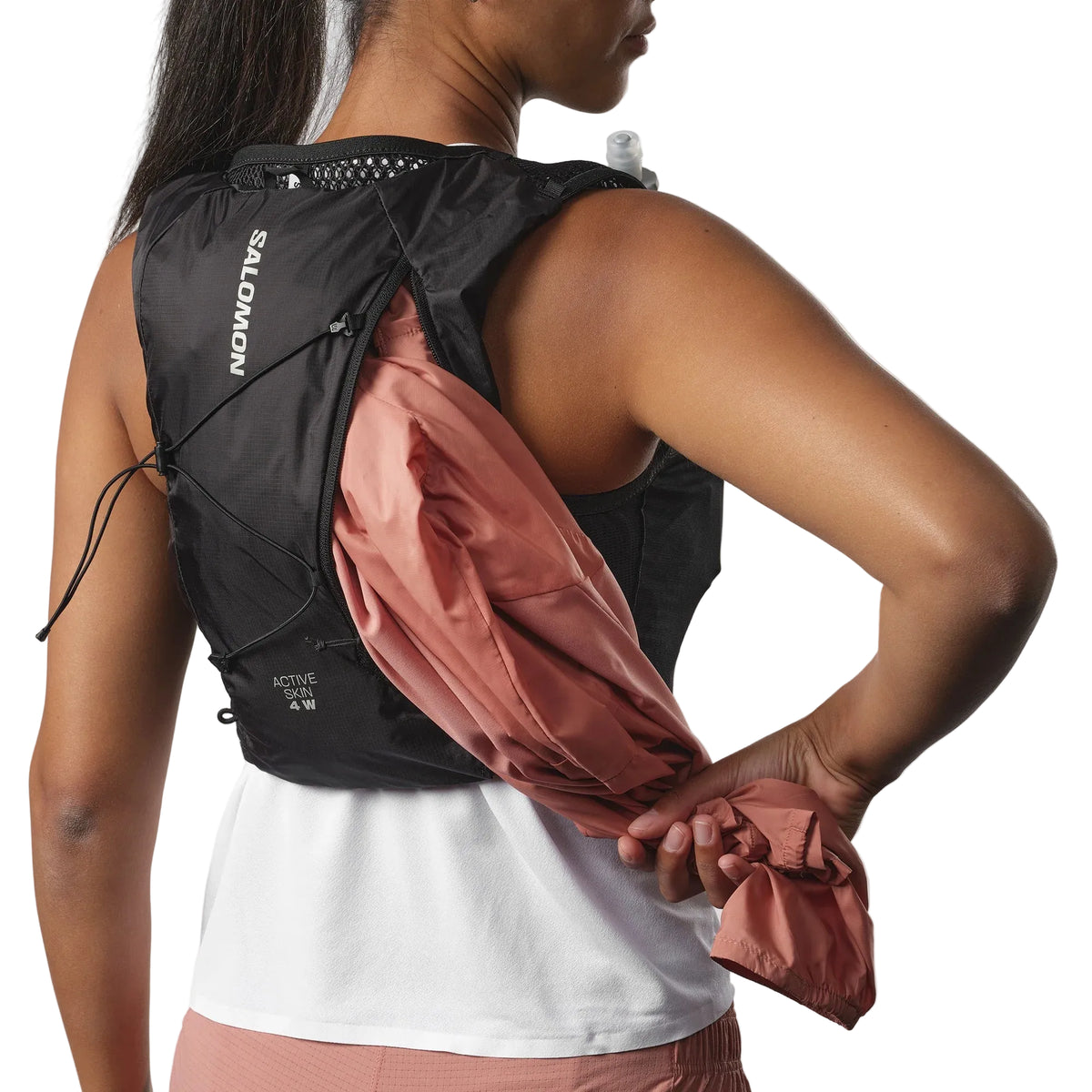 Person wearing a Salomon running vest with a pink jacket over it on a white background