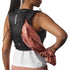 Person wearing a Salomon running vest with a pink jacket over it on a white background