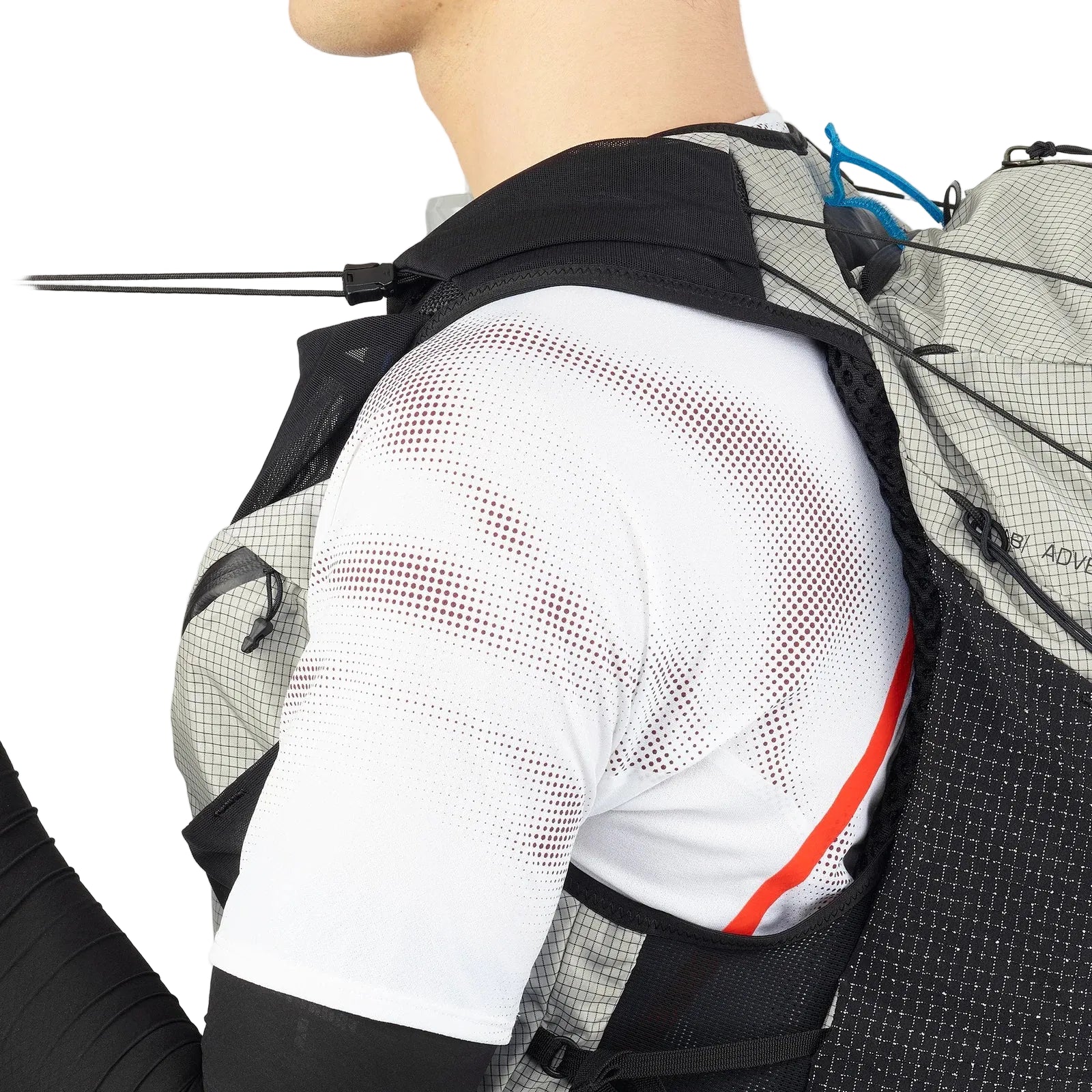Person wearing a black and gray backpack with a white shirt featuring red accents.