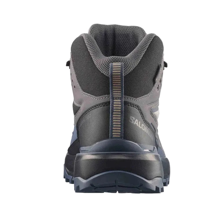 A Salomon mid-height hiking boot shown from the rear three-quarter view, featuring a dark gray and black mesh and synthetic upper with a textured pull tab and a rugged dark sole, set against a light gray background.