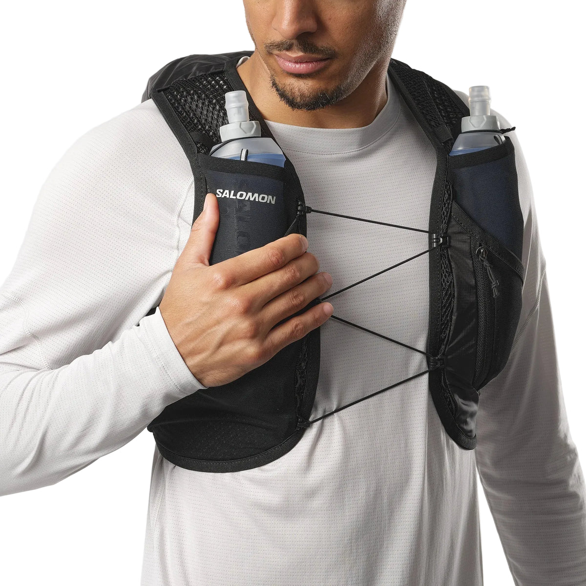 Person wearing a Salomon running vest with water bottles on a white background