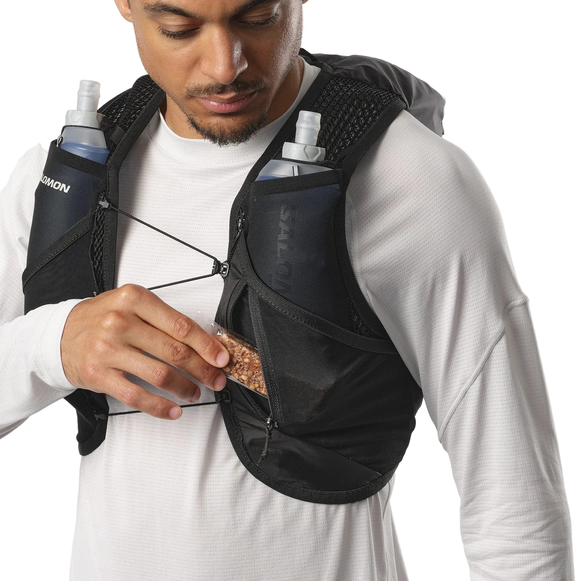 Person wearing a black hydration vest with water bottles and snacks.
