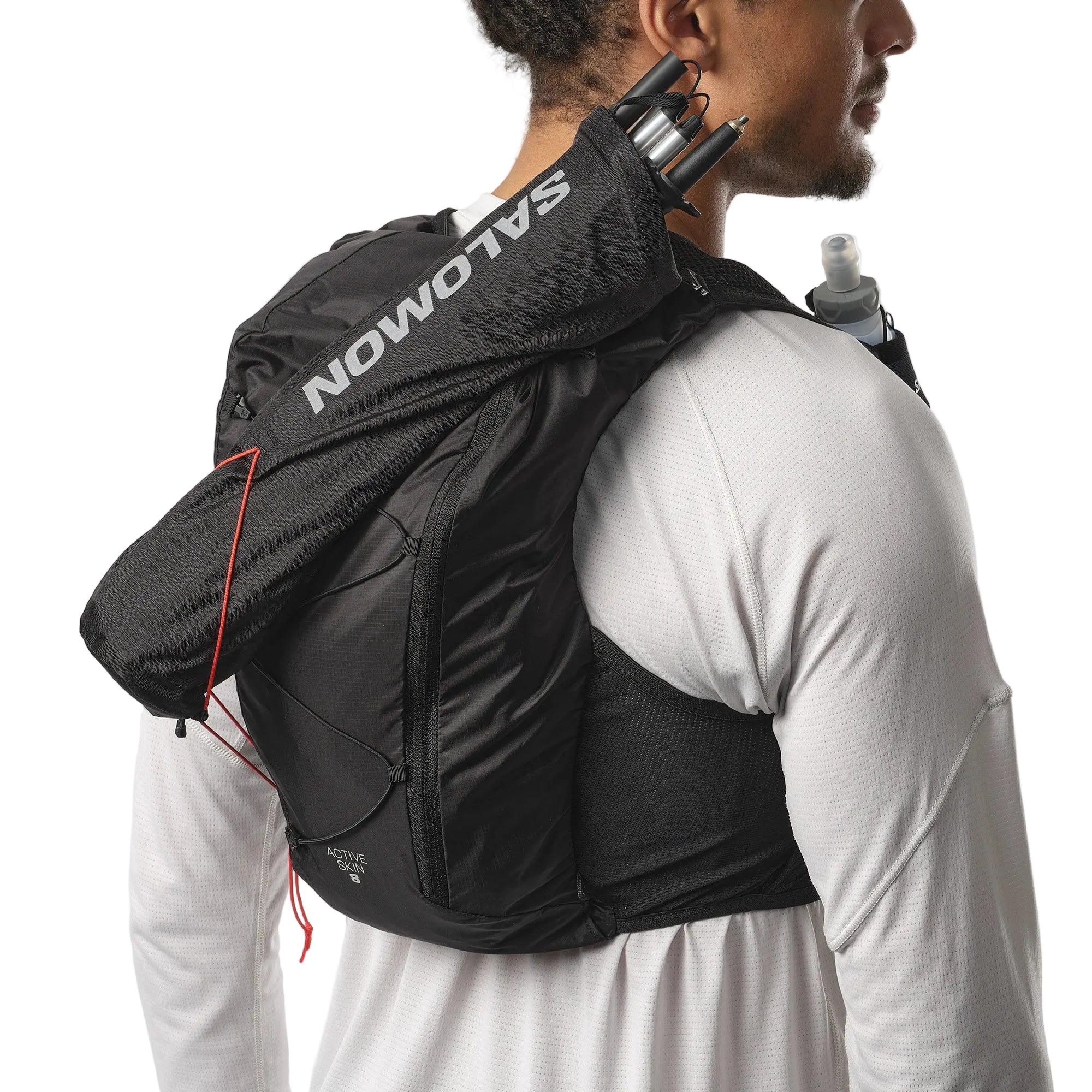 Person wearing a black Salomon running backpack with water bottles on a white background