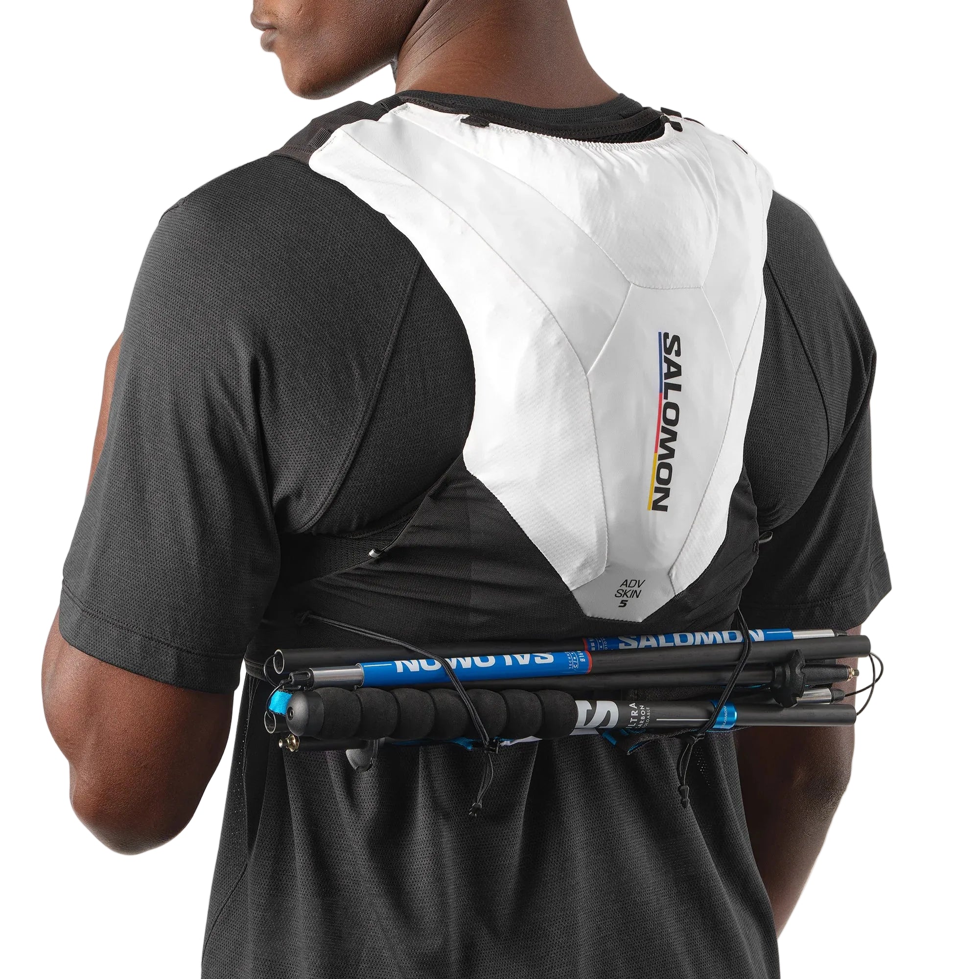 Person wearing a Salomon hydration pack with hiking poles on a plain background