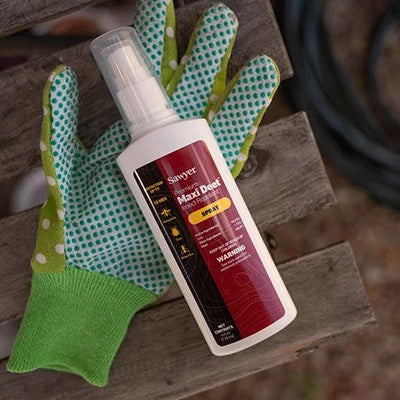 Sawyer Max Deet spray bottle with green gloves on a wooden surface