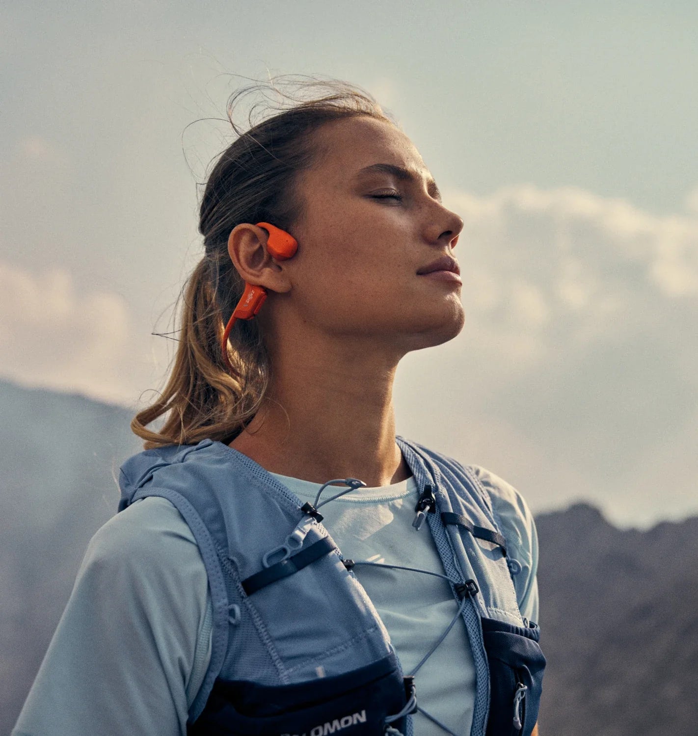 Person wearing wireless earbuds with mountains in the background