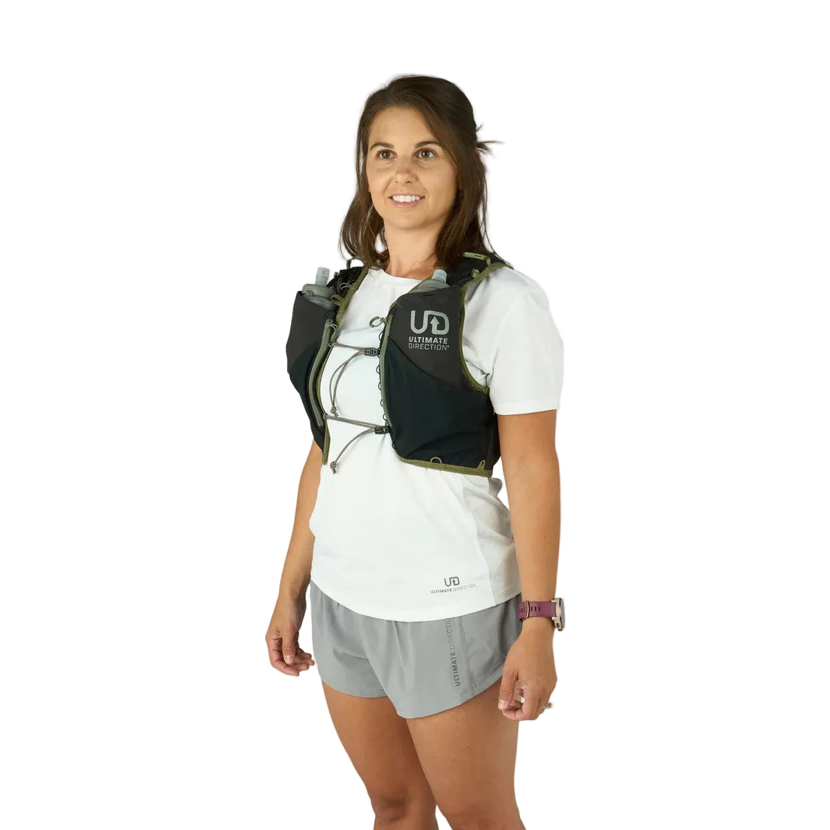 Woman wearing a hydration vest with 'Ultimate Direction' branding on a white background