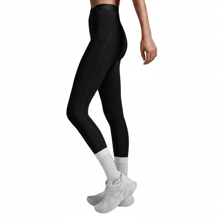 Person wearing black leggings and white sneakers on a gray background