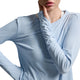 A close-up of a model wearing a light blue long-sleeve athletic top, showing the textured fabric and fit against a neutral gray background.