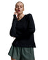 A woman modeling a black long-sleeve athletic top and olive green shorts against a light gray studio background.