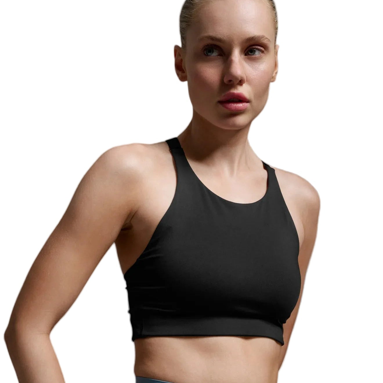 A woman modeling a black athletic crop top and light blue leggings against a neutral gray studio background.